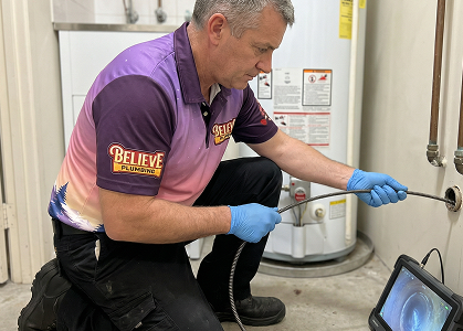 A Believe Plumbing technician reviewing a water heater job on a tablet with a homeowner